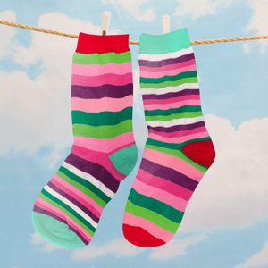 Colorful striped socks hanging on a clothesline with a blue sky and clouds in the background.