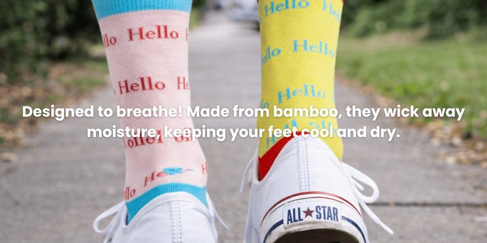 Colorful socks with 'Hello' text worn with white sneakers on a blurred outdoor background.