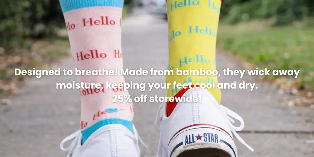 Person wearing colorful socks with 'Hello' text and white sneakers on a blurred outdoor background.