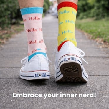 White sneakers with colorful socks and text on a paved path.