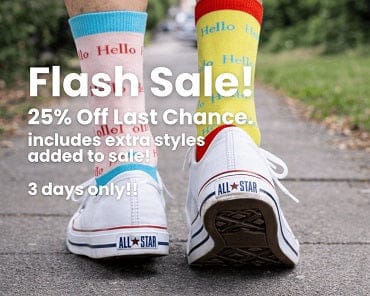 Person wearing colorful socks with 'Hello' text and All Star sneakers on a sidewalk.