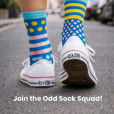Colorful socks with patterns worn on white sneakers on a street.