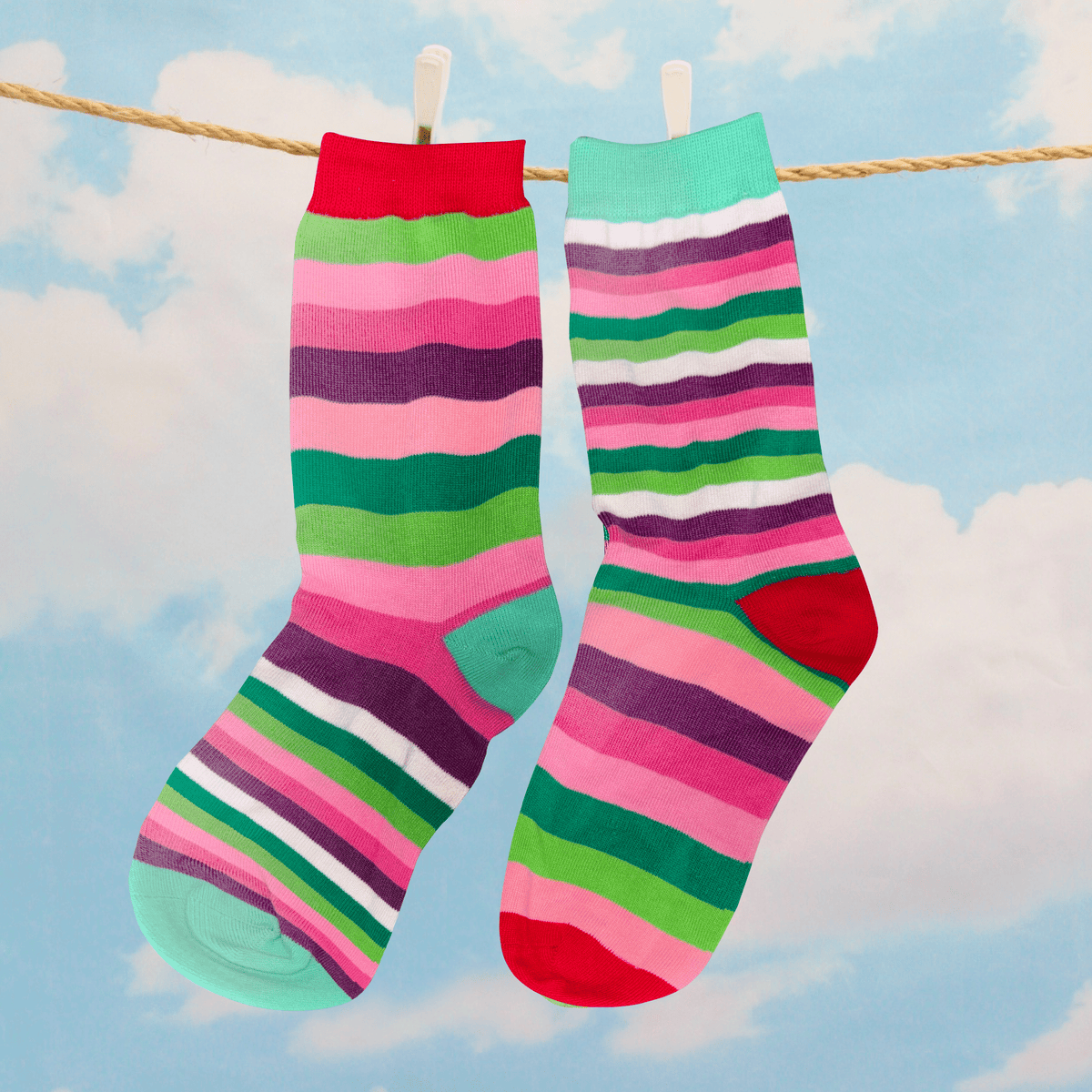 Colorful striped socks hanging on a clothesline with a blue sky and clouds in the background.

