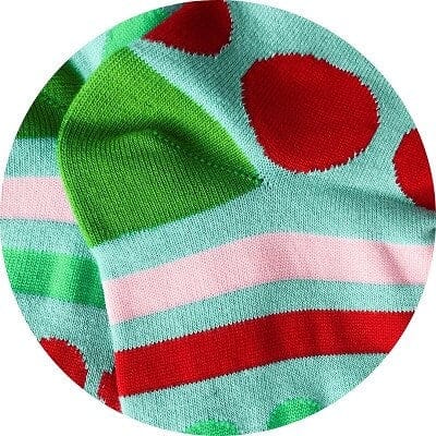 Colorful sock with red polka dots and green and pink stripes on a light blue background