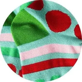 Colorful sock with red polka dots and green and pink stripes on a light blue background